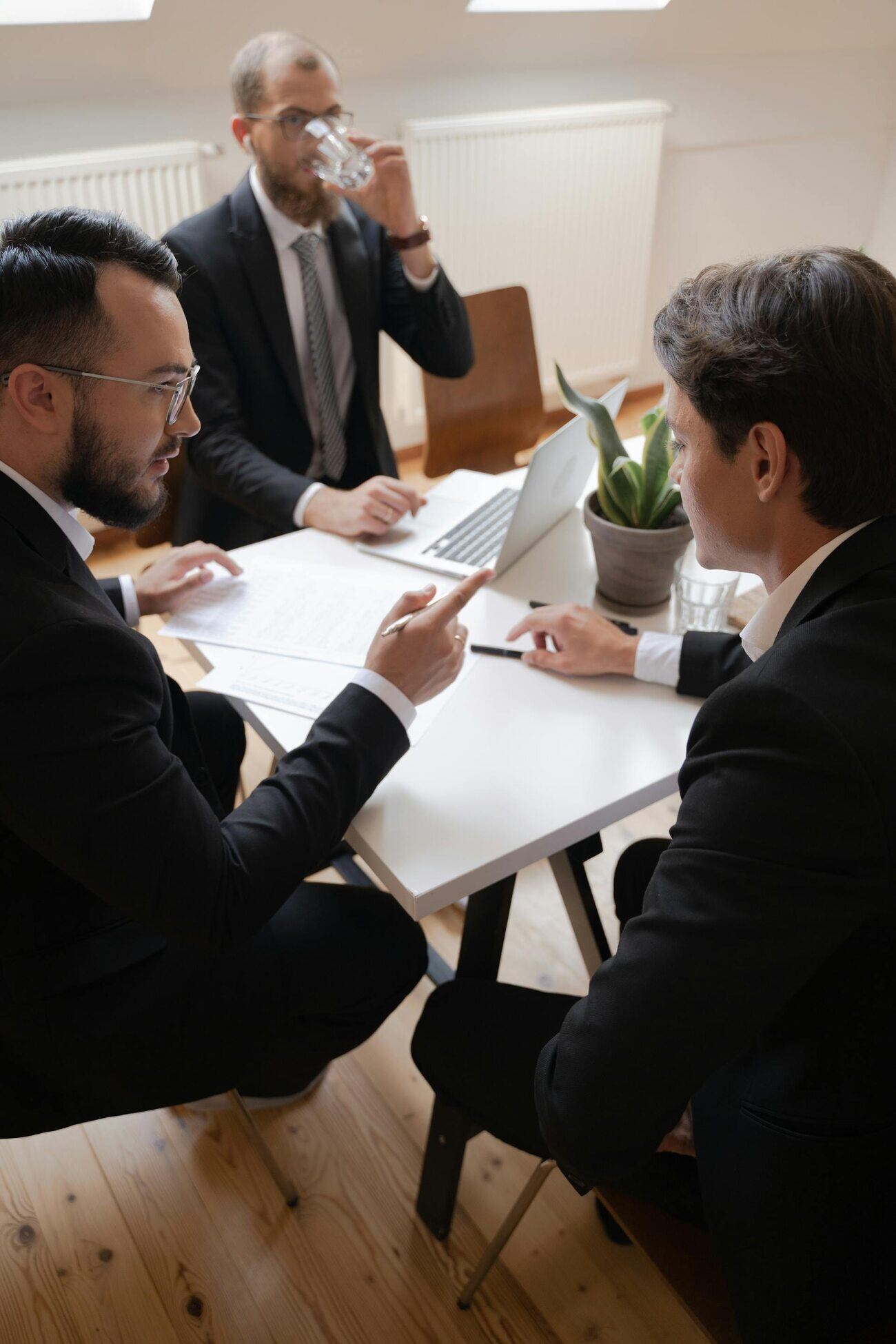 Three professionals working together at a table, each with a laptop open in front of them