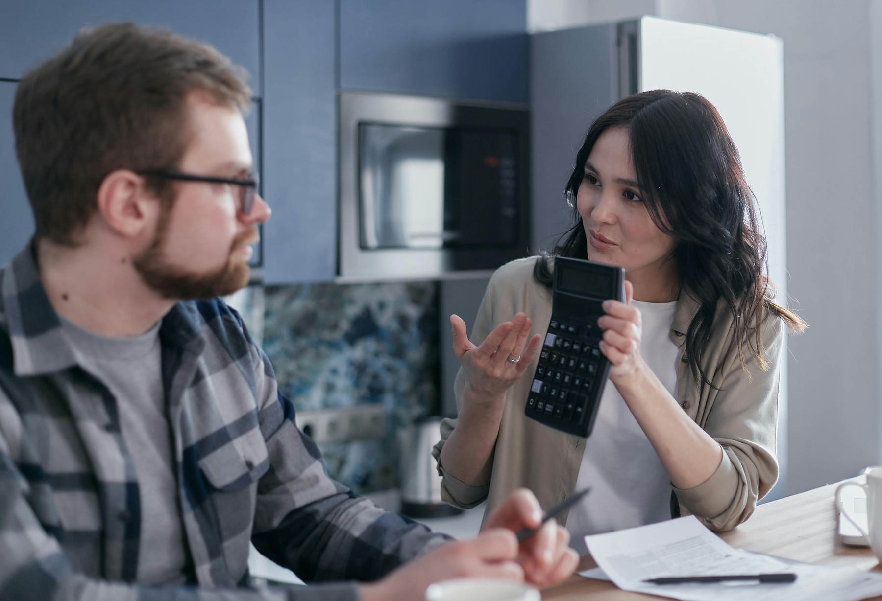 Woman showing a calculator result to her husband while they're planning their financial needs