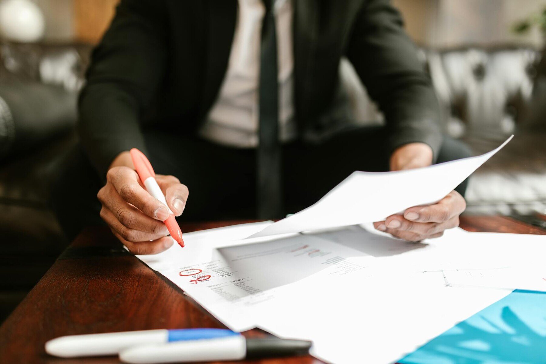 A man in a suit writing on a paper with a pen, focused and engaged in the task at hand