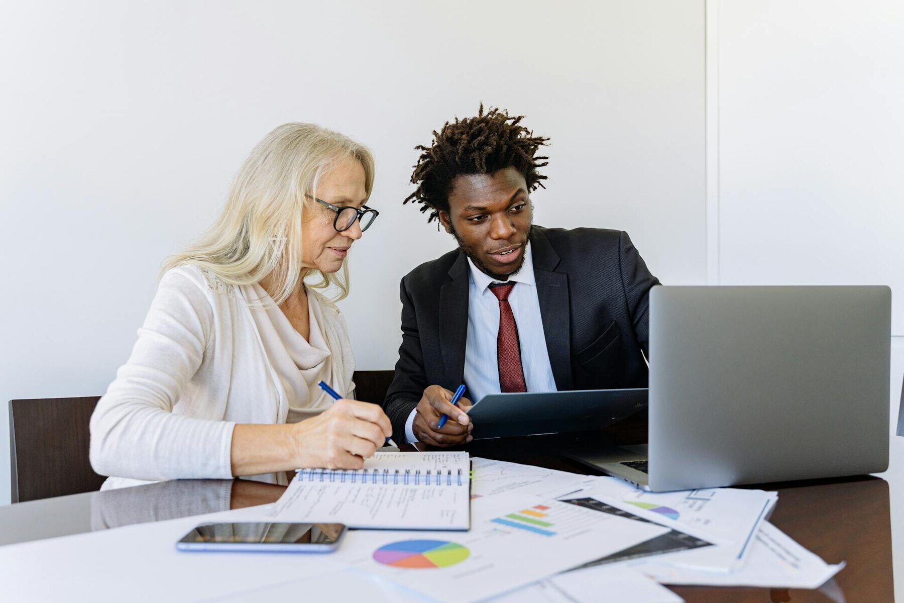 Two professionals in business attire sitting at a table with a laptop