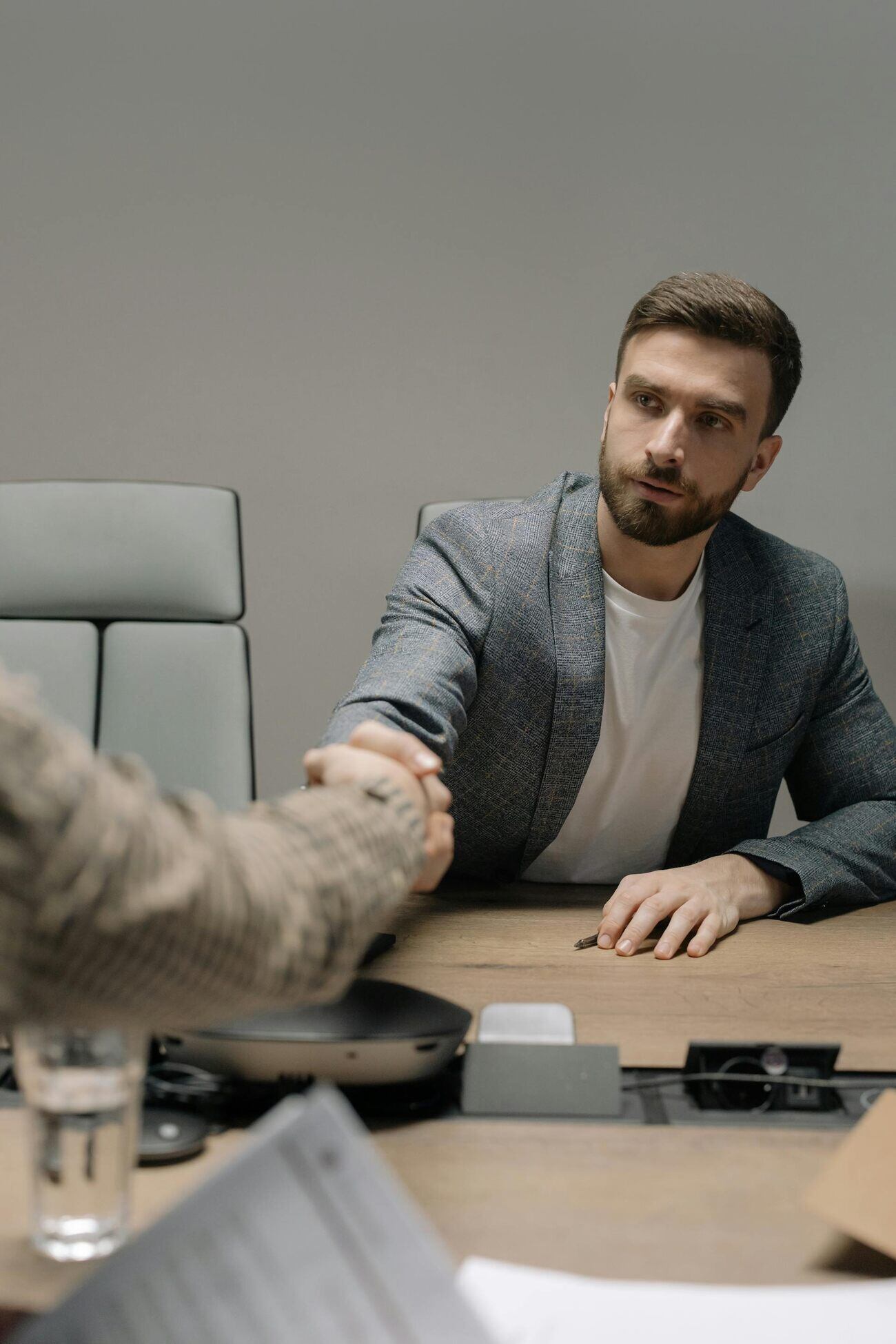Two businessmen shaking hands at a conference table during a meeting