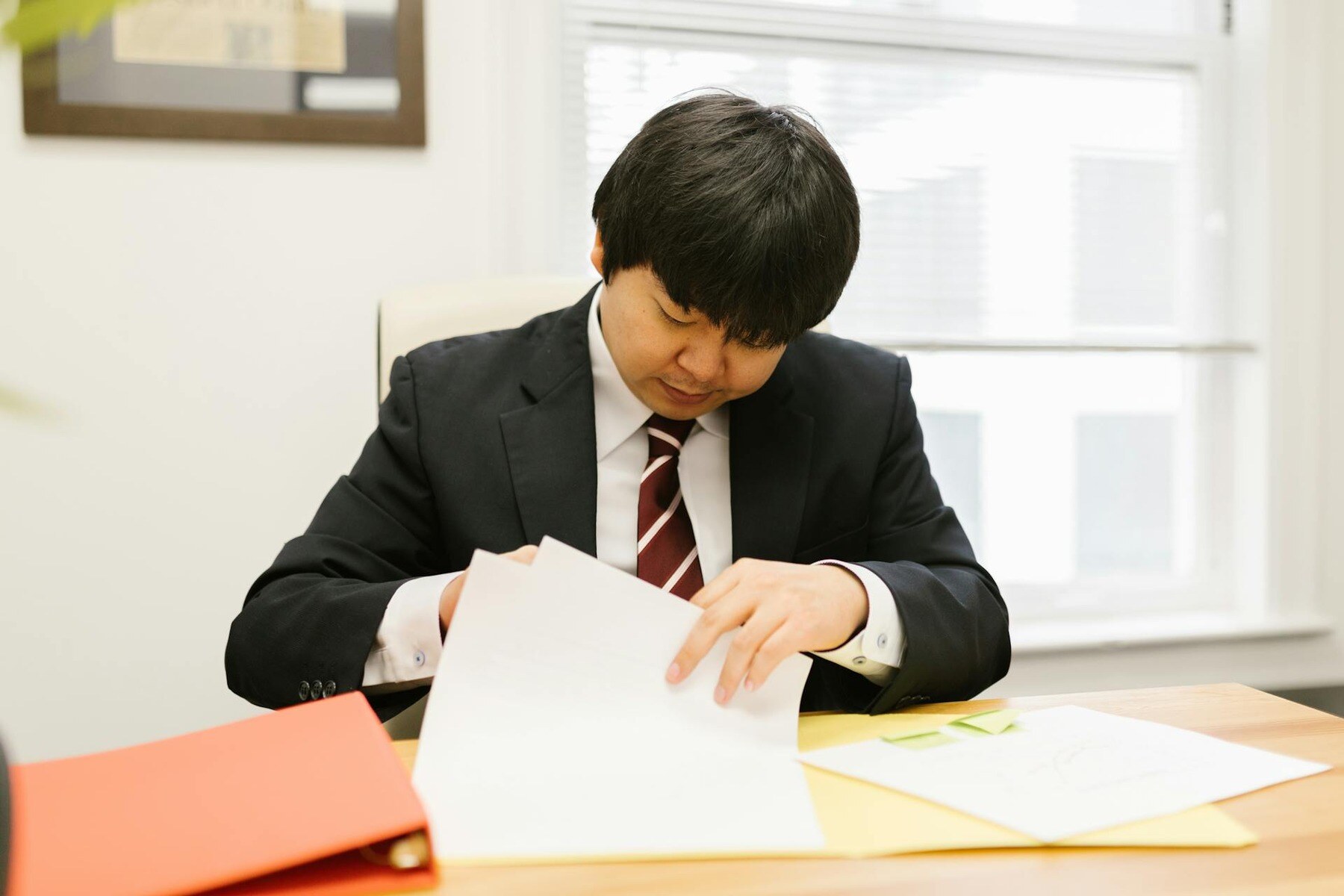 A businessman in formal attire reviews documents on a table