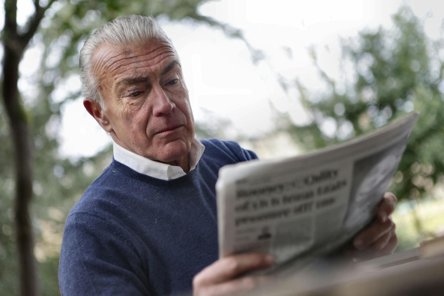 Elderly man reading newspaper